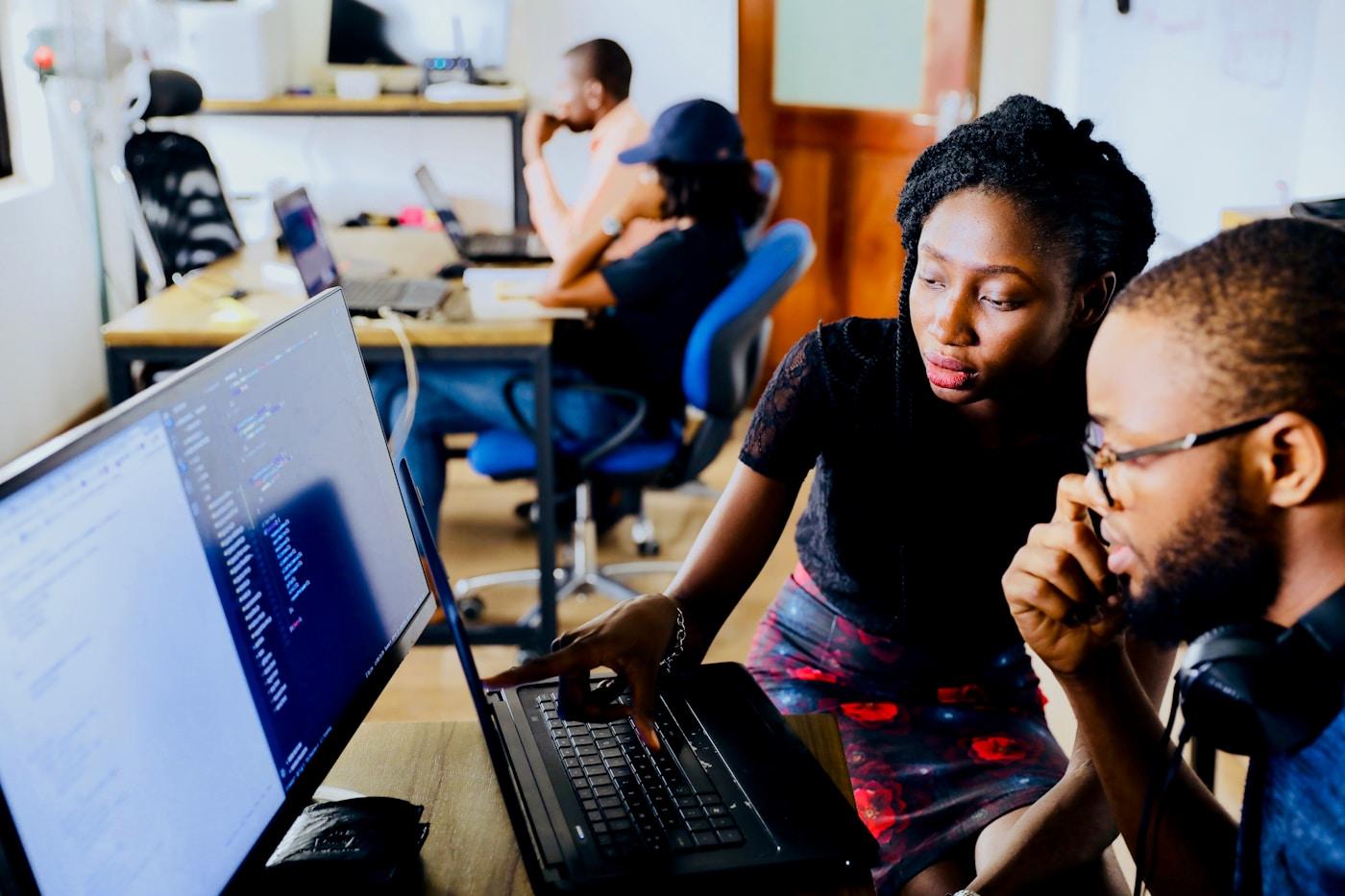 Engineers working together at laptops in a busy open-plan office.