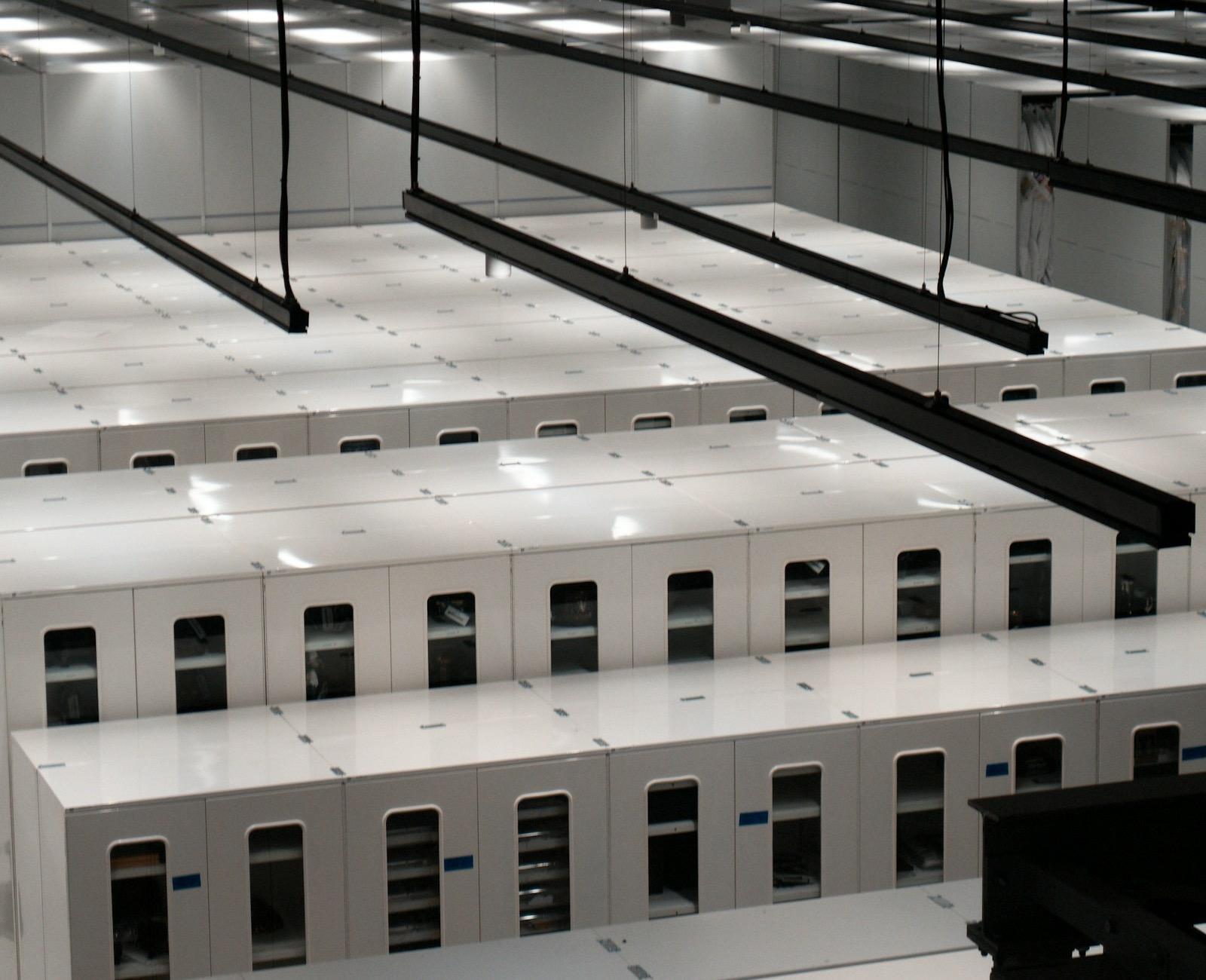 Rows of white server cabinets running the length of a data centre hall.