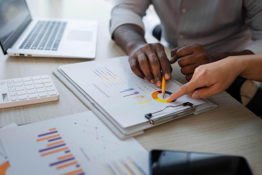 Two people annotating printed charts across a desk.
