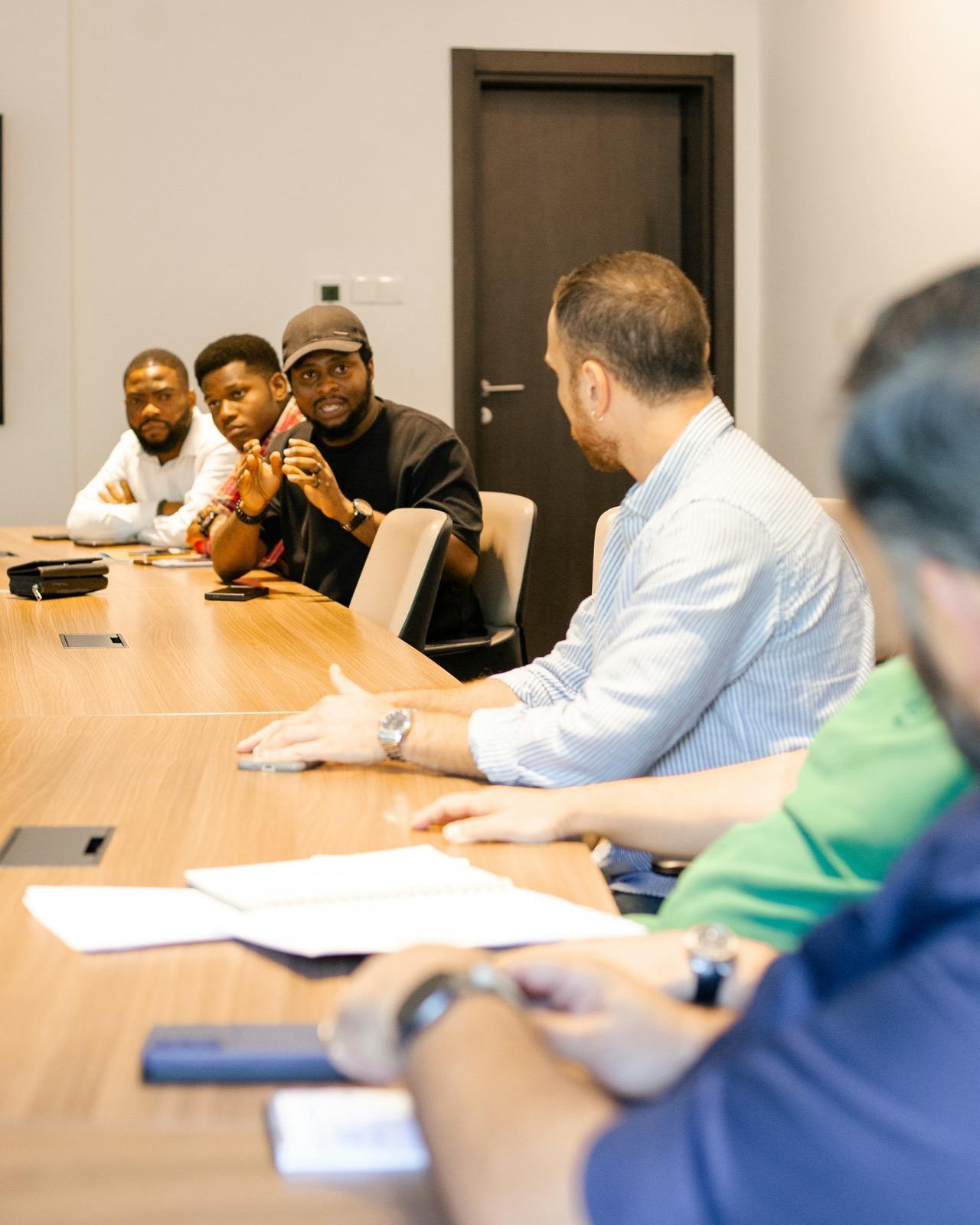 A working session around a boardroom table, one person mid-explanation.